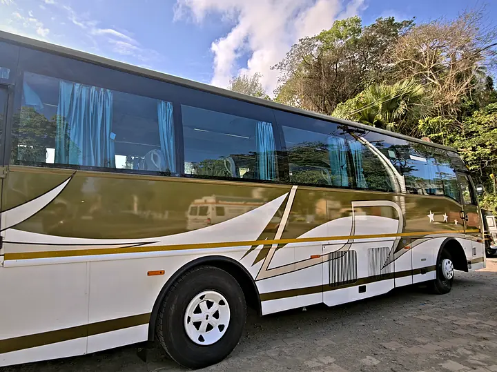 Side view of the gold and white tourist coach with curtained windows